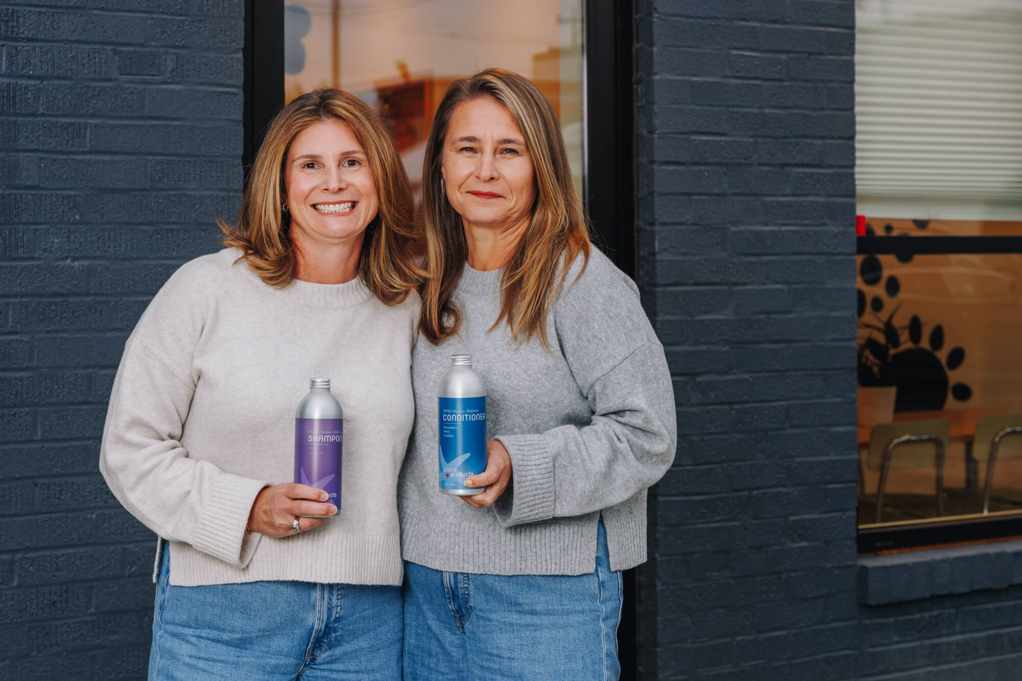 Plaine Products founders Ali and Lindsey with refillable aluminium bottles — sustainable hair and body care made in the USA